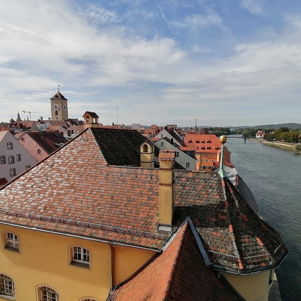 A red tiled roof building overlooking a river.